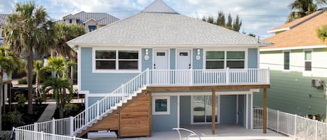 A two-story house with a balcony, a pool, and a staircase leading to the upper floor.