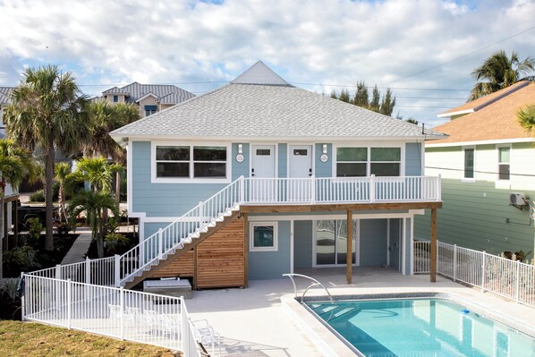 A two-story house with a balcony, a pool, and a staircase leading to the upper floor. - The June  (Fort Myers Beach)