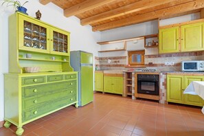 Una cocina con armarios verdes, un refrigerador, un horno y un microondas.