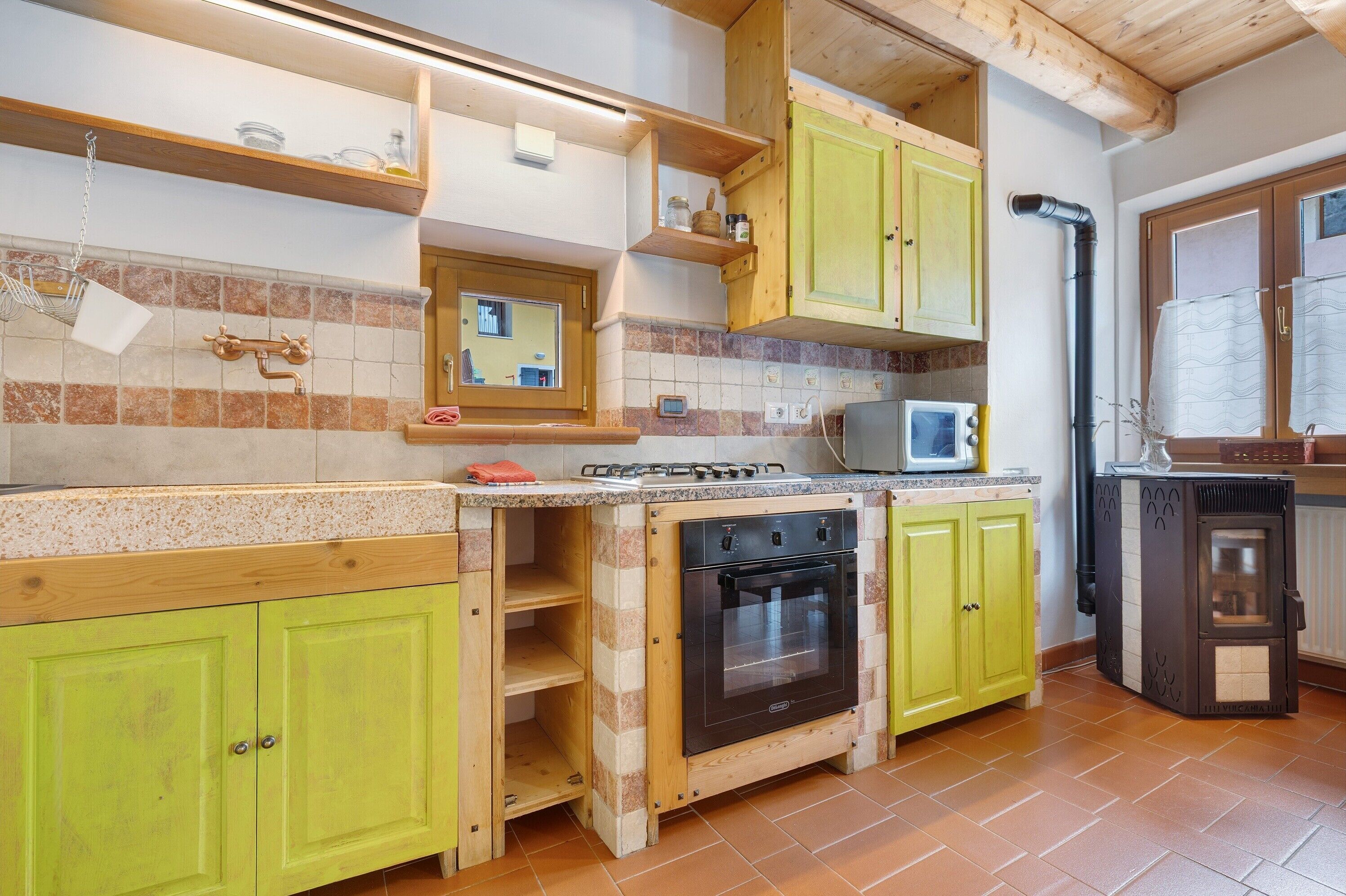 A kitchen with wooden cabinets, a stove, a microwave, and a wood-burning stove.