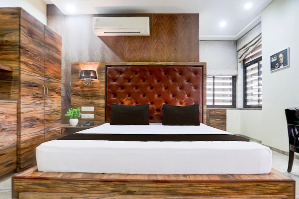 Une chambre à coucher avec un grand lit, une armoire en bois et un climatiseur fixé au mur.