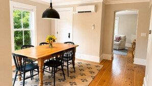 A dining area with a wooden table, black chairs, a black pendant light, and a floral rug. - Falmouth Foreside Cottage Escape - Luxe Kitchen + Walk to the Water! (Falmouth)