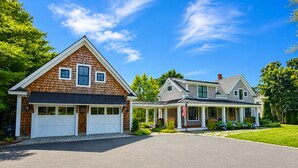 A two-story house with a garage and a covered porch. - Falmouth Foreside Cottage Escape - Luxe Kitchen + Walk to the Water! (Falmouth)