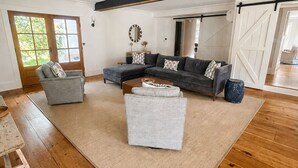 A spacious living room with a sectional sofa, a grey armchair, and a large rug. - Falmouth Foreside Cottage Escape - Luxe Kitchen + Walk to the Water! (Falmouth)