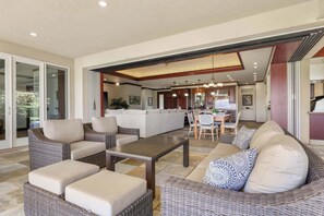 A spacious living area with a sofa set, a dining table, and a kitchen in the background. - Wai'ula'ula Villa 345 Three Bedroom (Kohala Coast)