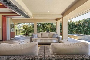 A spacious outdoor seating area with a sofa and two armchairs, a pergola overhead, and a view of a landscaped garden. - Wai'ula'ula Villa 345 Three Bedroom (Kohala Coast)