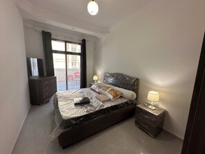 Un dormitorio con cama, mesitas de noche, cómoda y ventana, con vistas al exterior.