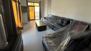 Una sala de estar con sofá, mesa de centro, televisor y puerta corrediza de vidrio que da a un balcón.