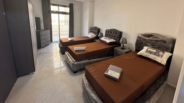 Habitación de hotel con dos camas, un armario, un escritorio y vistas al exterior.