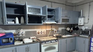 Una cocina con gabinetes grises, un microondas integrado, una estufa a gas y un lavamanos.