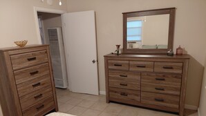 Un dormitorio con cama, cómoda, espejo y armario.