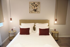 Una cama bien hecha con almohadas blancas y rojas, un cabecero de madera y una obra de arte colgada en la pared.