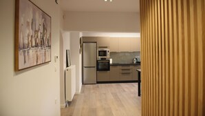 A modern kitchen with stainless steel appliances, a wooden floor, and a painting on the wall. - CozyFlat 88m2 very spacious for long stays, fully equipped, with private parking (Mitilini)