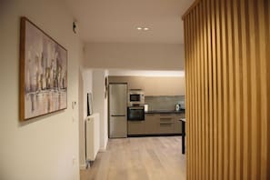 Eine moderne Küche mit Edelstahlgeräten, Holzboden und einem Gemälde an der Wand.