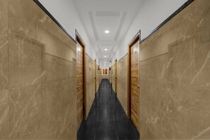 A corridor with marble walls and black flooring, leading to a door at the end. - Deluxe Srinika Inn (Hyderabad)