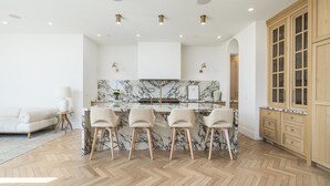 Una cocina moderna con salpicadero de mármol, armarios de madera y una zona de bar con taburetes.