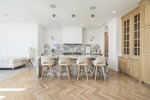 A modern kitchen with marble backsplash, wooden cabinets, and a bar area with stools. - “Paris Has Its Brownstones. Phoenix Has 54 W Palm.” (Phoenix)