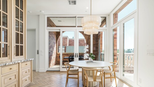 Una cocina amplia con armarios de madera, encimera de mármol y una mesa redonda con sillas.