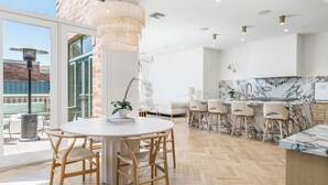 Una cocina moderna con encimera de mármol, sillas de madera y una zona de comedor con mesa redonda y sillas.