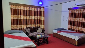 Une chambre avec deux lits, un canapé, une table basse et des rideaux.