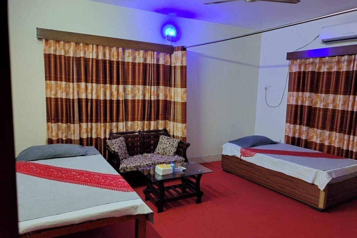 Una habitación con dos camas, un sofá, una mesa de centro y cortinas.