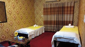 Une chambre avec deux lits, une petite table sur laquelle est posé un vase de fleurs et un miroir au mur.