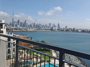 Ein Balkon mit Blick auf eine Stadtlandschaft, ein Gewässer und ein Schwimmbecken.