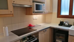 A kitchen with a microwave, oven, and a window. - Charming bungalow with garden in a quiet neighborhood (Montreuil)