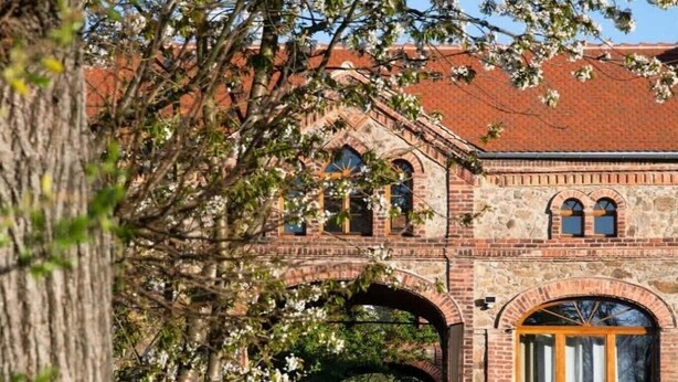 A brick building with arched windows and a wooden door. - A Two-storey Home With Terrace and Fireplace - Last Minute (Grossharthau)