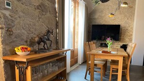 A dining area with a stone wall, wooden furniture, a bowl of fruit, and a mounted horse sculpture. - A Two-storey Home With Terrace and Fireplace - Last Minute (Grossharthau)