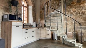 A kitchen with white cabinets, a microwave, and a stone wall. - A Two-storey Home With Terrace and Fireplace - Last Minute (Grossharthau)