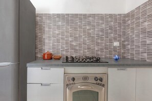 Une cuisine compacte équipée d’un four encastré, d’une cuisinière à gaz et d’un four à micro-ondes.