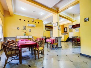 A restaurant with yellow walls, wicker furniture, and tiled flooring. - Super Townhouse Calangute (Calangute)