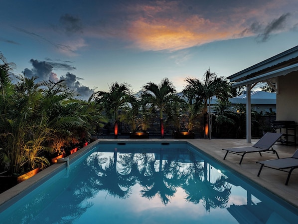Ein Swimmingpool mit Palmen und Blick auf den Sonnenuntergang.