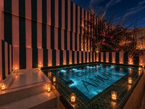 A rectangular pool with 'Castilla Amor' written on the tiles, surrounded by a tiled deck with candles.