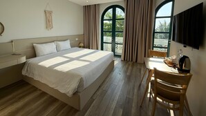 Une chambre d’hôtel équipée d’un lit, d’un bureau, d’une chaise, d’une télévision et de grandes fenêtres.
