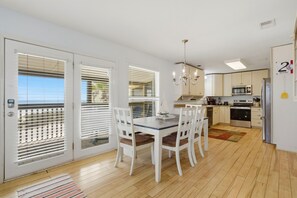 A modern kitchen with white cabinets, a dining table with chairs, a chandelier, and a refrigerator. - NEW LISTING - PRIVATE BEACH HOME!! Seaswept in Fort Morgan - Great Gulf Views (Gulf Shores)