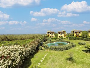 A residential area with multiple yellow buildings, a swimming pool, and a well-maintained garden. - Holiday Home With air Conditioning and Shared Pool (Viddalba)