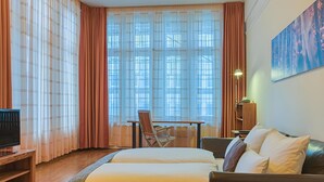 Une chambre d’hôtel avec un lit, un bureau, une chaise, une télévision et un tableau au mur.