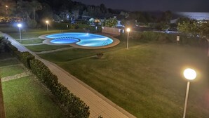 Vista nocturna de una piscina con senderos y luces a su alrededor.