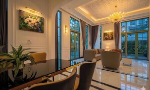 A spacious living area with a glass coffee table, comfortable seating, large windows, and a chandelier. - Opus Villas Tropical Phu Quoc (Phu Quoc)