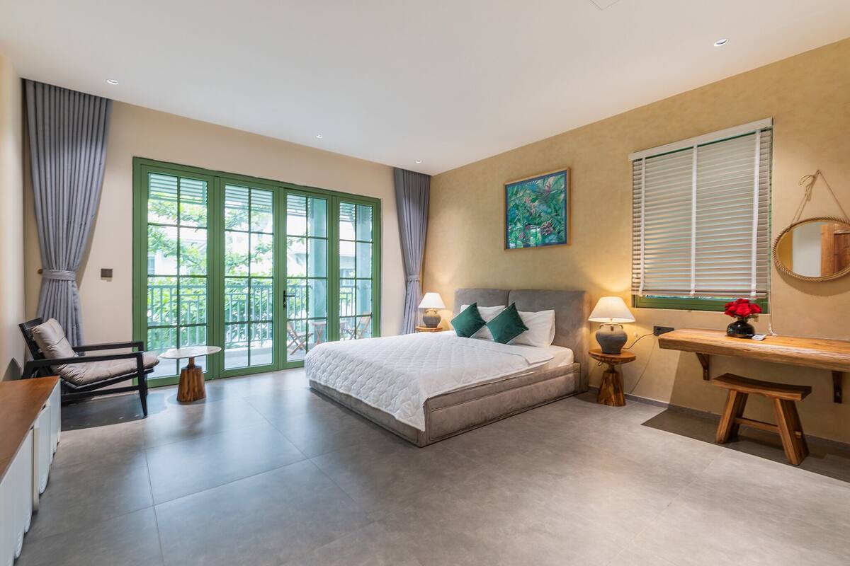 A bedroom with a bed, a desk, a chair, and a window with curtains.