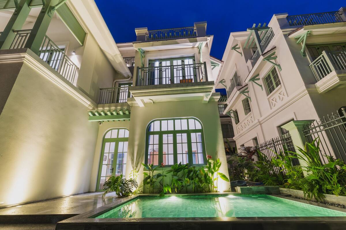 A multi-story building with a swimming pool, balconies, and a gated entrance.
