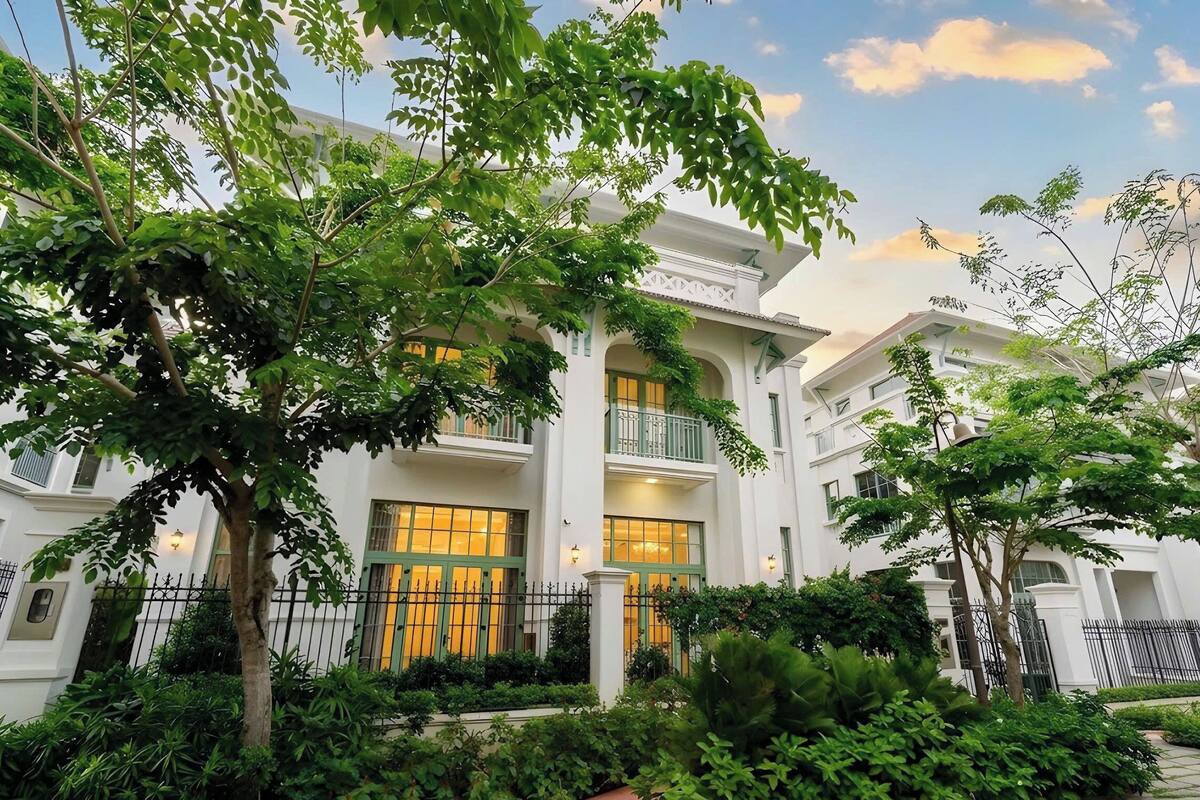 A multi-story building with balconies, surrounded by greenery.