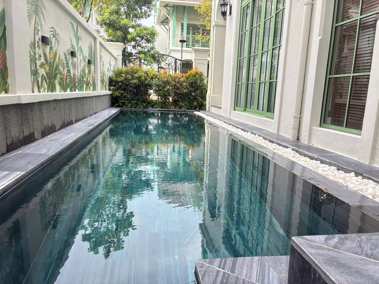Una piscina con superficie de agua cristalina, rodeada por un muro bajo de superficie texturizada.