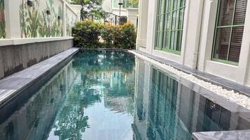 Una piscina con superficie de agua cristalina, rodeada por un muro bajo de superficie texturizada.