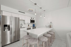 Eine moderne Küche mit Edelstahlgeräten, weißen Schränken und einer Bar mit Sitzhocker.