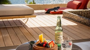 A wooden deck with a table, a bottle of mineral water, a glass of water, and a fruit platter. - Luxury Adults-Only Oceanfront Escape in Beautiful Cancun (Cancún)