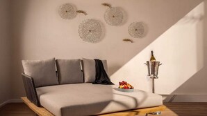 A modern sofa with a wooden frame, a small table with fruit, decorative wall pieces, and a bottle of champagne. - Luxury Adults-Only Oceanfront Escape in Beautiful Cancun (Cancún)