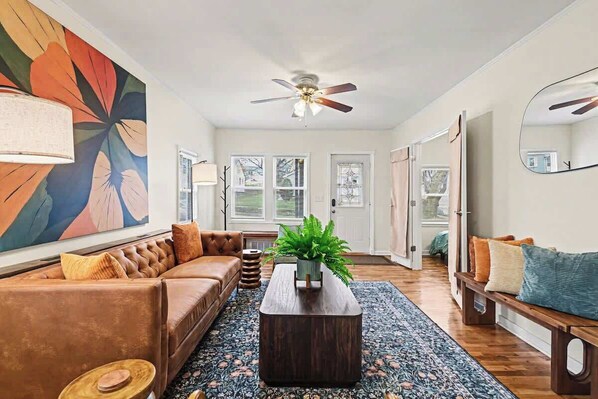 A living room with a sofa, coffee table, and a large abstract painting on the wall. - Stylish 4BR Retreat | 2-Car Garage | Sleeps 10 (Omaha)